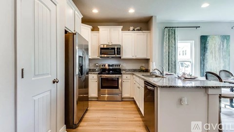 A modern kitchen with white cabinets and stainless steel appliances.