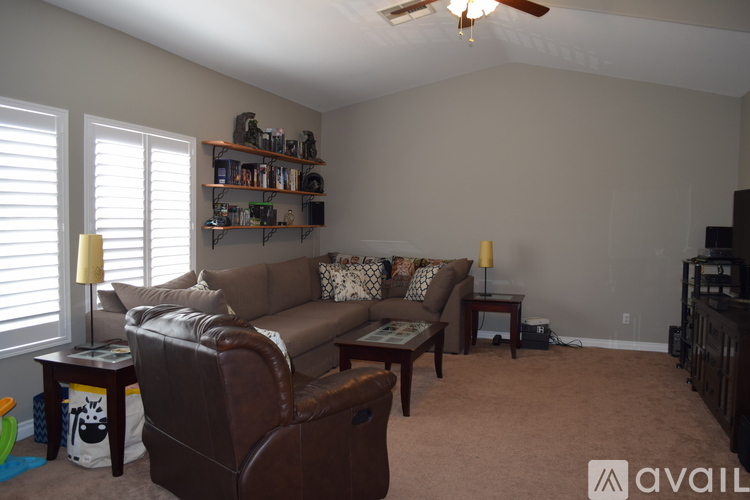 A living room with a brown leather couch and a ceiling fan.