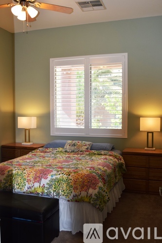 A bedroom with a floral bedspread and two lamps.