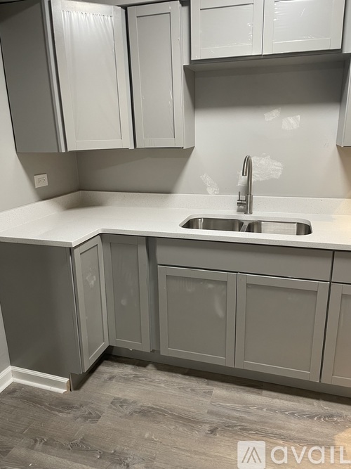 A kitchen with grey cabinets and a white countertop.