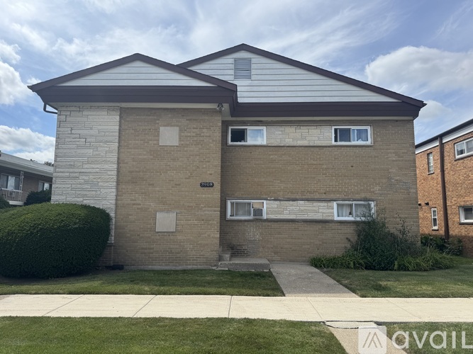 A two-story brick apartment building with a balcony on the second floor.