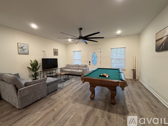 A living room with a pool table and a television.