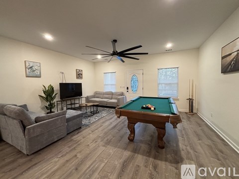 A living room with a pool table and a television.