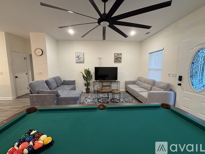 A pool table with balls and a TV in the background.
