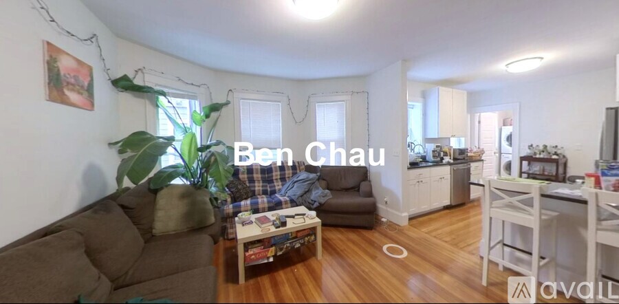 A living room with a couch, a chair, a coffee table, and a potted plant.