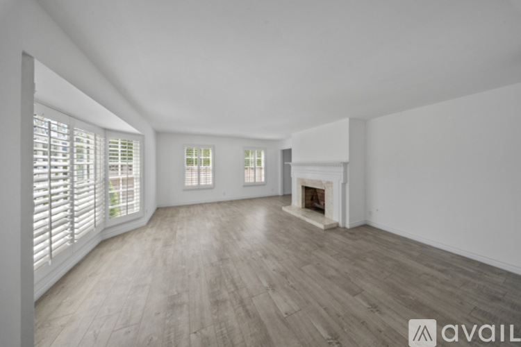 A spacious room with wooden flooring and a fireplace.