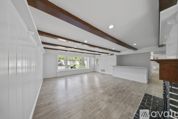 A spacious room with wooden floors and white walls.