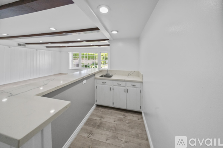 A kitchen with white cabinets and a countertop is available for rent.