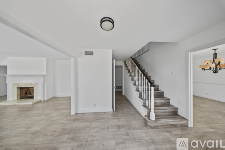 A spacious living room with a fireplace and a staircase.