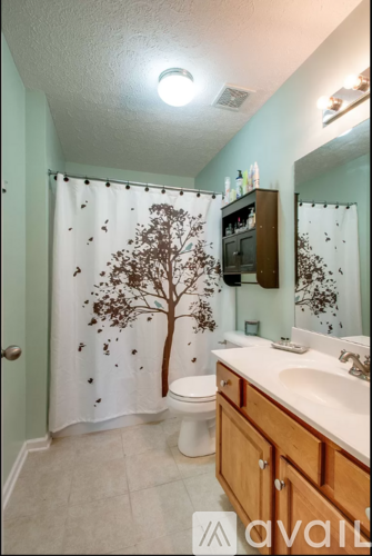 A bathroom with a tree design on the shower curtain.