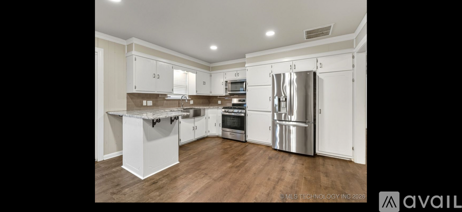 A modern kitchen with white cabinets and stainless steel appliances.