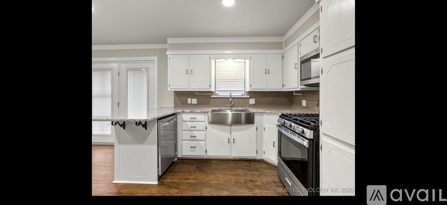 A kitchen with white cabinets and a black stove top oven.