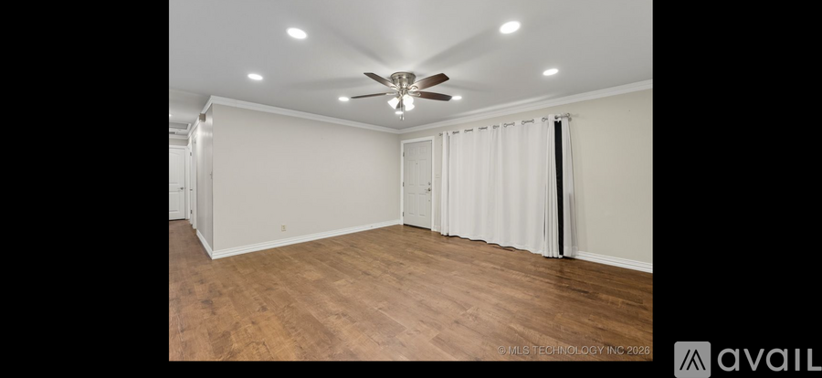 A spacious room with a ceiling fan and wooden flooring.