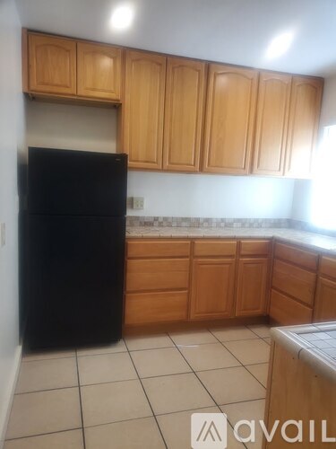 A kitchen with wooden cabinets and a black refrigerator.