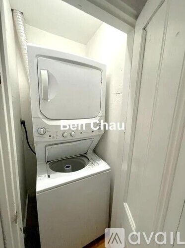 A small white washing machine is in a narrow space.