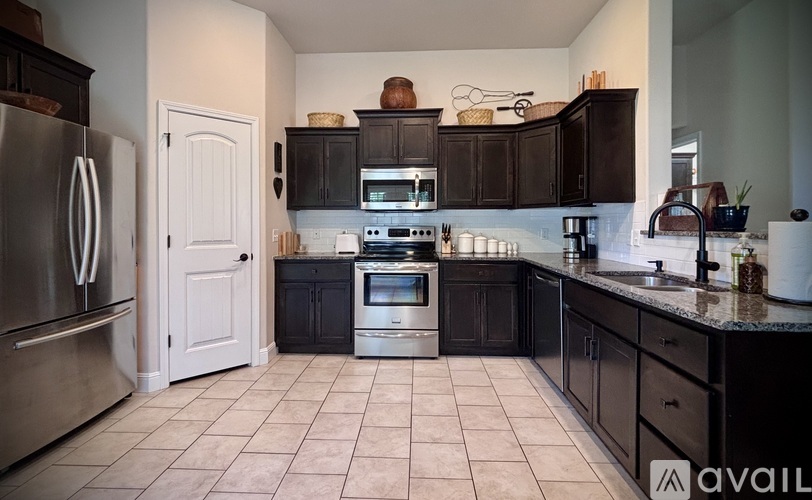 A kitchen with black cabinets and a white door.