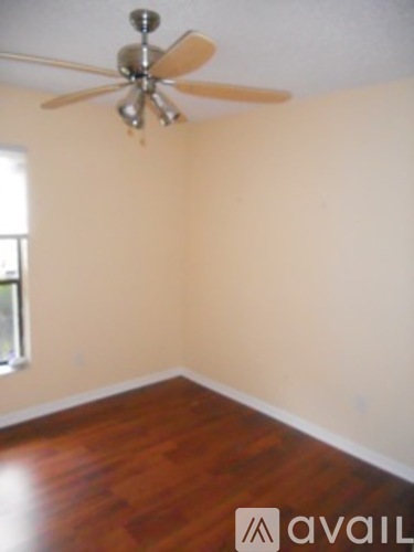 A room with a ceiling fan and wooden floors.