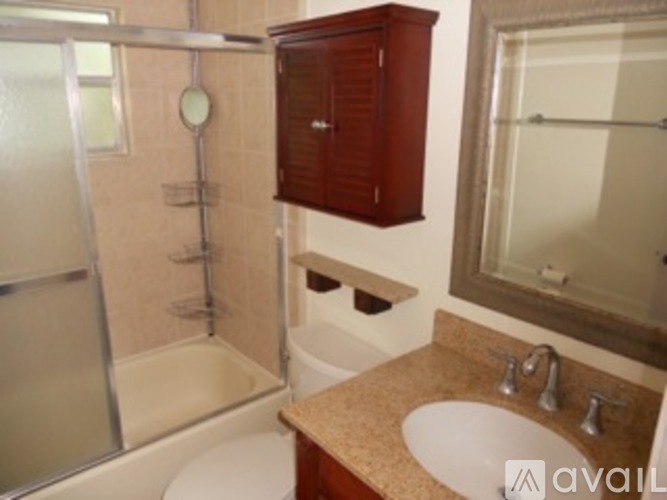 A bathroom with a brown cabinet and a glass shower door.