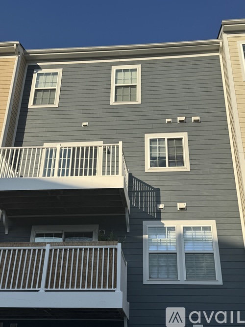 A grey building with a white balcony and a white sign that says "AVAIL".