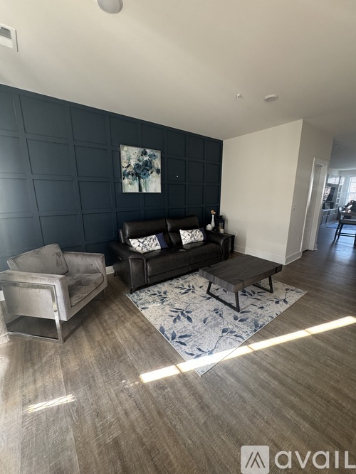 A living room with a black couch and a grey armchair.