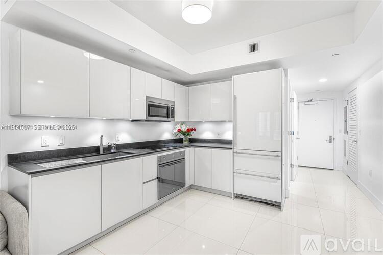 A modern kitchen with white cabinets and a black countertop.