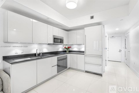 A modern kitchen with white cabinets and a black countertop.