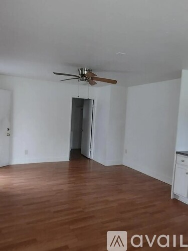 A room with a ceiling fan and wooden flooring.