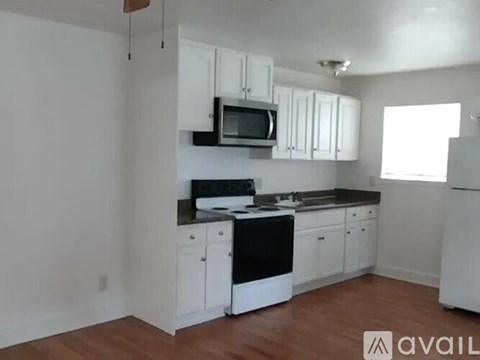 A kitchen with white cabinets and black appliances.