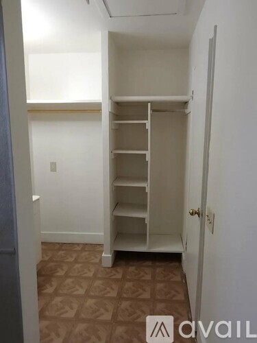 A room with a white closet and brown tiled floor.