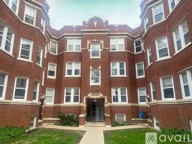 A large red brick building with a central entrance and a green lawn in front.