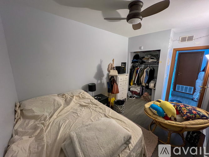 A bedroom with a bed, a ceiling fan, a wardrobe, and a chair.