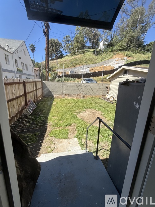 A view from a window looking out to a backyard with a fence and a car parked in the distance.