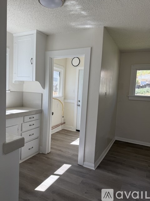 A kitchen with white cabinets and a grey floor.