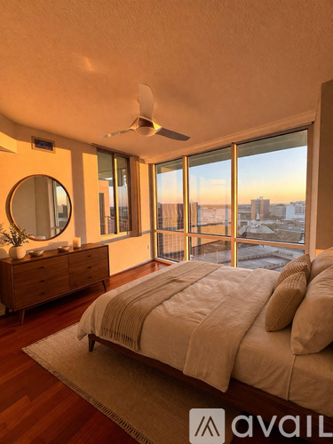 A bedroom with a large bed and a view of the city at sunset.