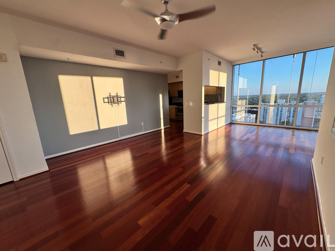 A spacious room with wooden floors and a ceiling fan.