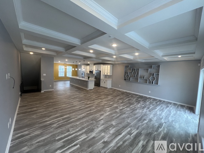 A spacious room with wooden flooring and a large window.