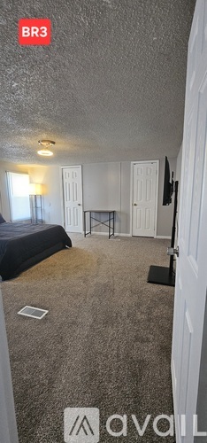 A bedroom with a bed, a desk, and a television.