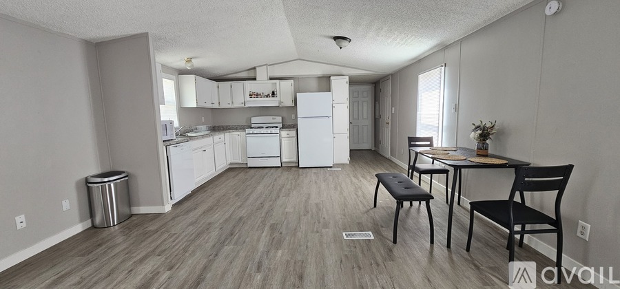 A kitchen with a dining table and chairs in the foreground.