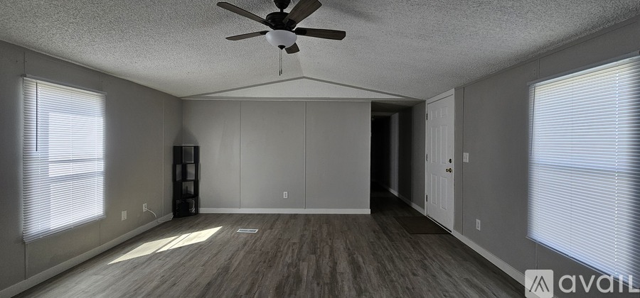 A spacious room with a ceiling fan and wooden flooring.
