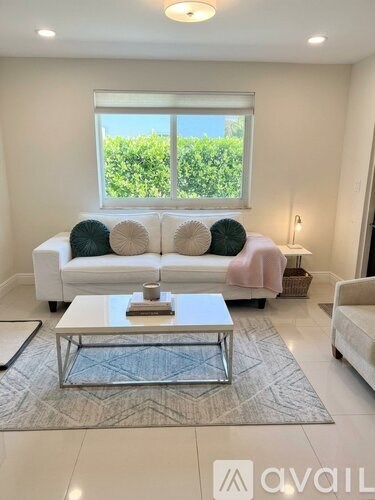 A living room with a white couch and a glass coffee table.