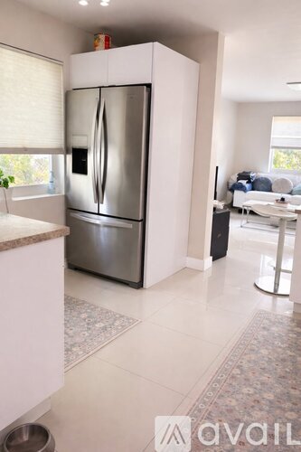 A modern kitchen with a stainless steel refrigerator and a dining area in the background.