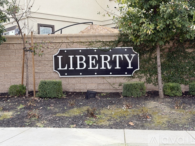 A black and white sign that says "LIBERTY" is in front of a house.