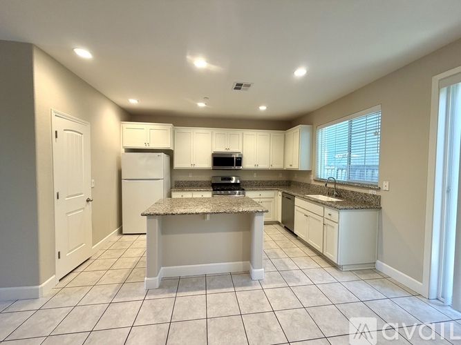 A kitchen with white cabinets and a granite countertop.