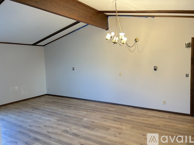 A room with wooden flooring and a chandelier hanging from the ceiling.