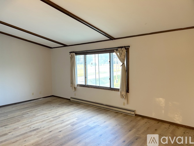 A room with a window and wooden flooring is available for rent.