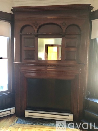 A large wooden fireplace with a black screen in front.