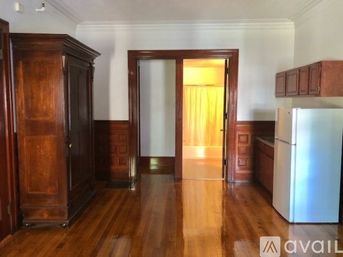A room with wooden floors and furniture, and a white refrigerator.