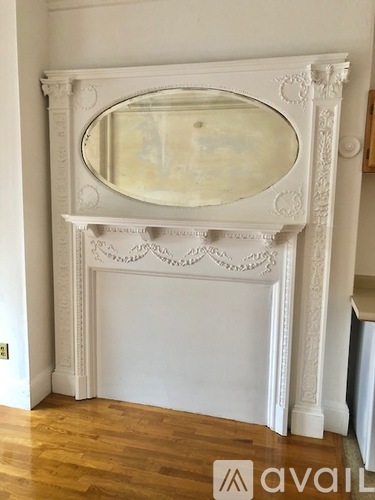 A white fireplace with a mirror above it.