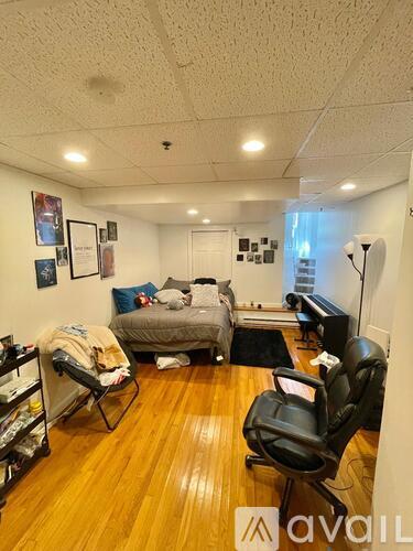 A room with a bed, chair, and pictures on the wall.