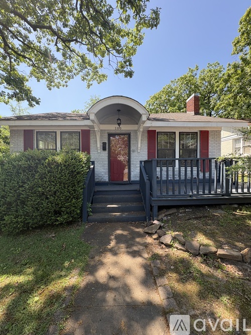 A red and white house with a black front door and steps leading to a porch.